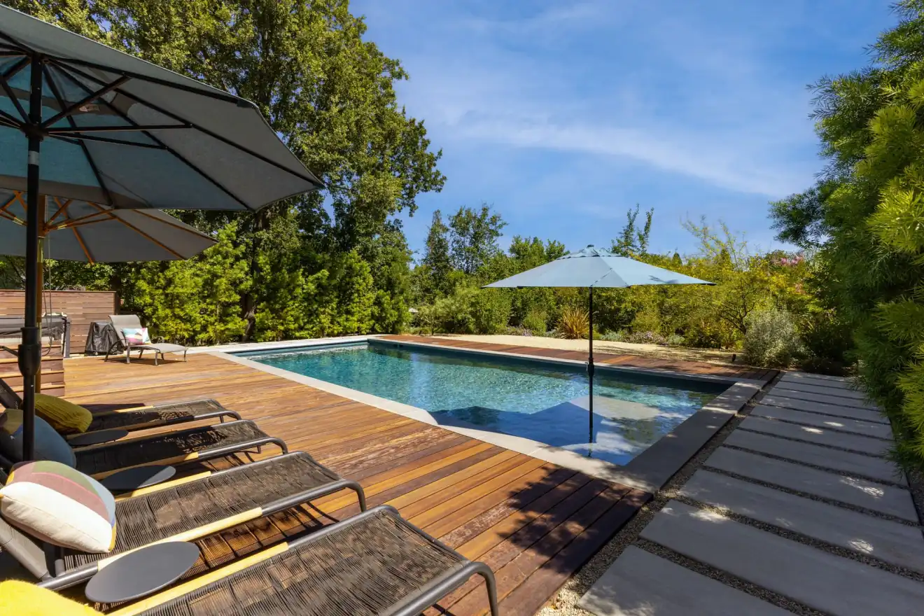 Backyard gunite pool with wood deck at dusk