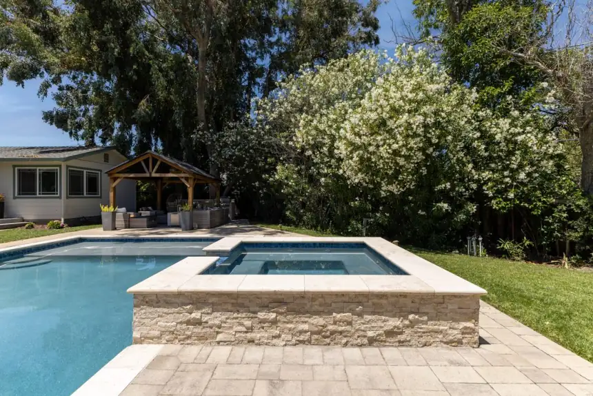 Gunite pool and raised spa with stone facing and paver deck built by King's Pools